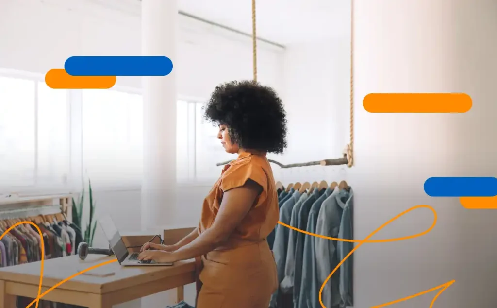 Mujer utilizando un ordenador en un comercio local de ropa, realizando la facturación electrónica